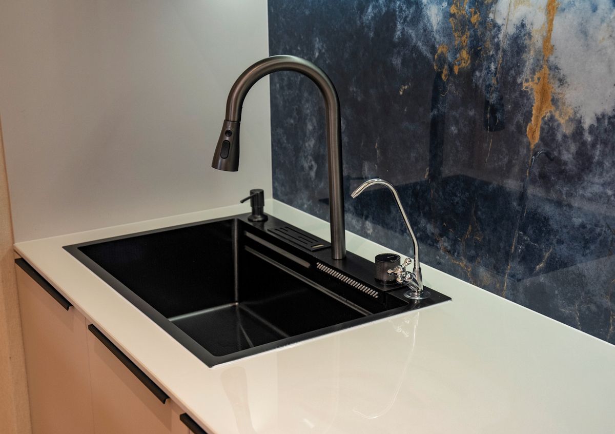 Matt black kitchen tap and sink against a marble splashback