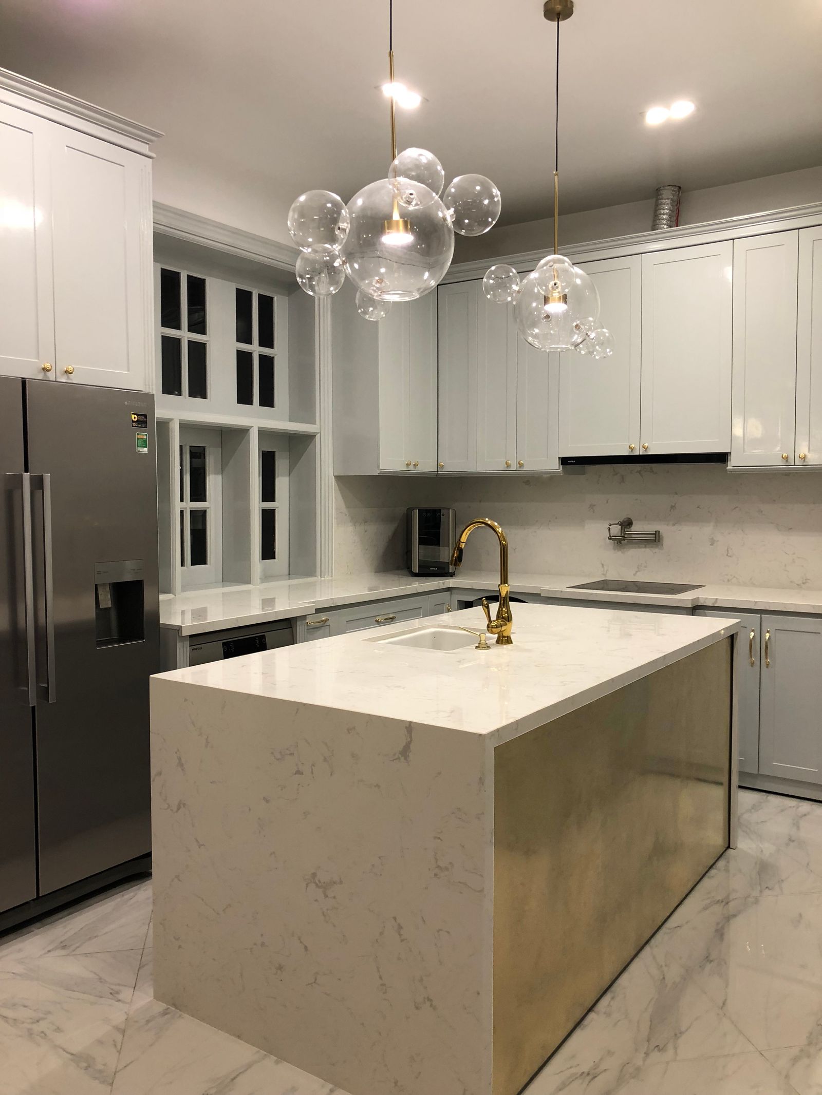 Grey shaker kitchen with marble waterfall island and brass pendants