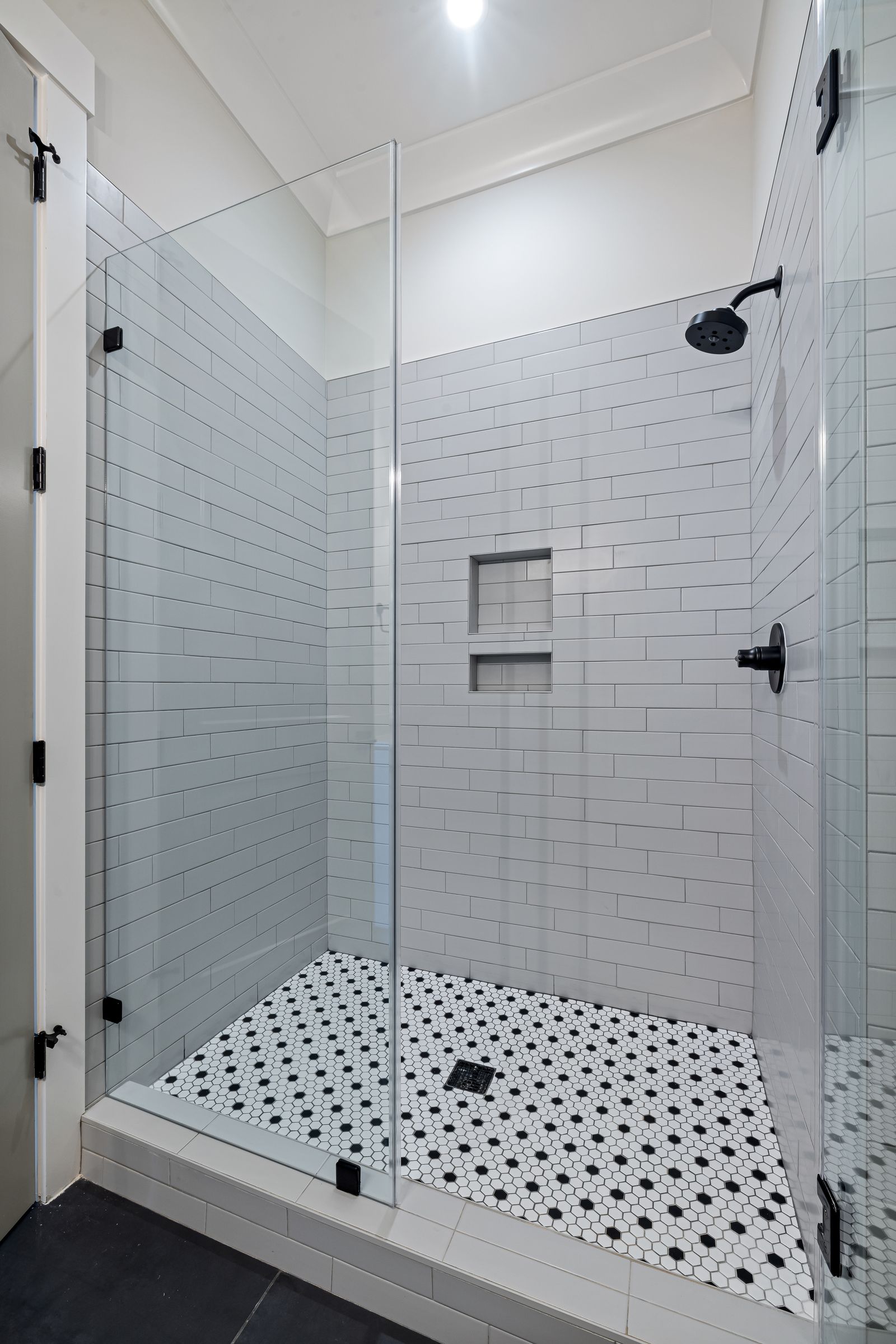 Subway tiled shower with mosaic floor and black fittings